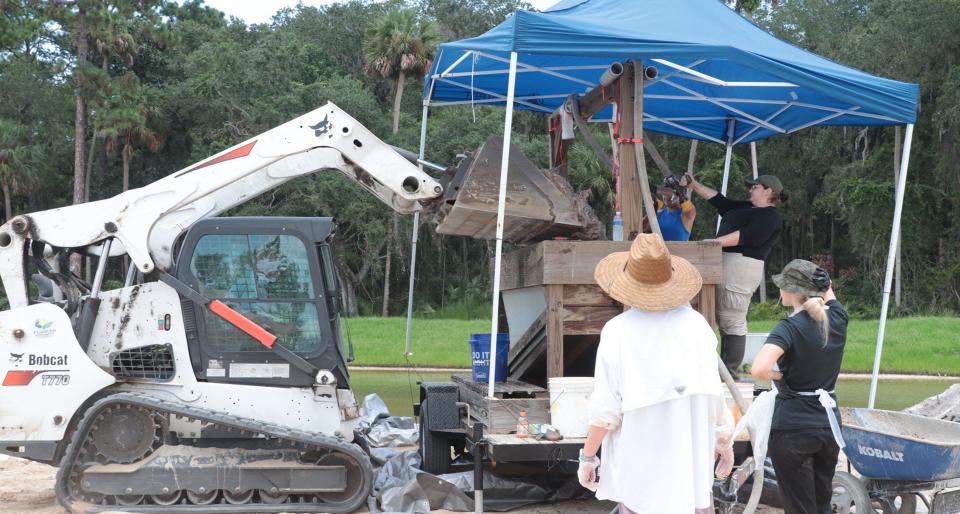 A Bobcat adds more dirt to a wash table, Wednesday, July 27, 2022, as a USF team works the dig site where human bones were found July 18 in the Toscana development in Palm Coast.