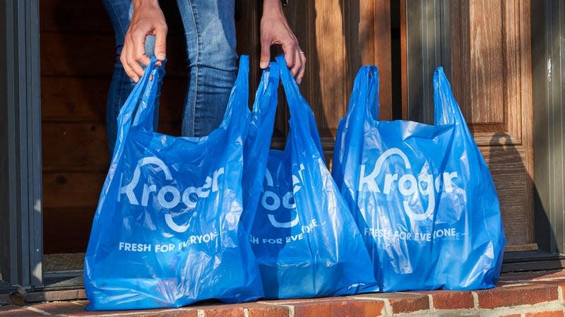 3 Kroger plastic shopping bags sit on a stoop