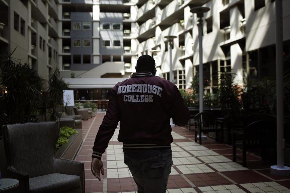 In this Tuesday, May 5, 2020, photo, Morehouse College senior Lanarion "LTL" Norwood Jr., of Atlanta, walks through a hotel lobby in Atlanta. Students were sent home from the college amid the new coronavirus outbreak. (AP Photo/Brynn Anderson)