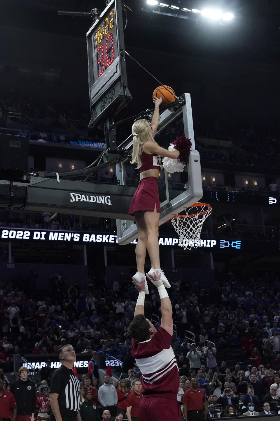 An Arkansas cheerleader reaches for a ball stuck on the top of the glass during the second half of a college basketball game between Duke and Arkansas in the Elite 8 round of the NCAA men's tournament in San Francisco, Saturday, March 26, 2022. (AP Photo/Marcio Jose Sanchez)