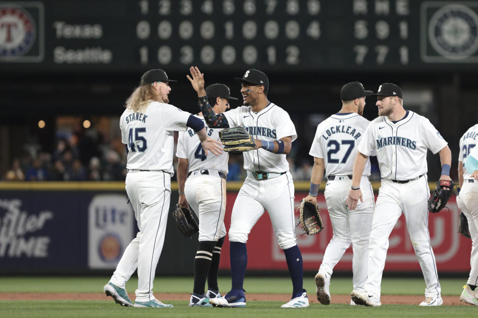 Seattle Mariners closing pitcher Ryne Stanek (45) high-fives outfielder Julio Rodríguez as players celebrate a win over the Texas Rangers in a baseball game Saturday, June 15, 2024, in Seattle. The Mariners won 7-5. (AP Photo/Jason Redmond)