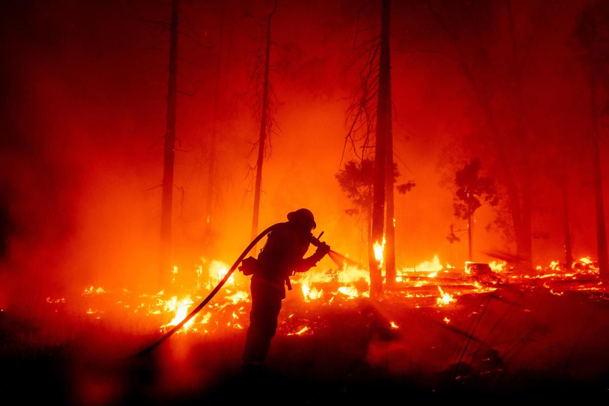 A firefighter battles the Creek Fire as it threatens homes in the Cascadel Woods neighborhood of Madera County, Calif ((Noah Berger via AP))