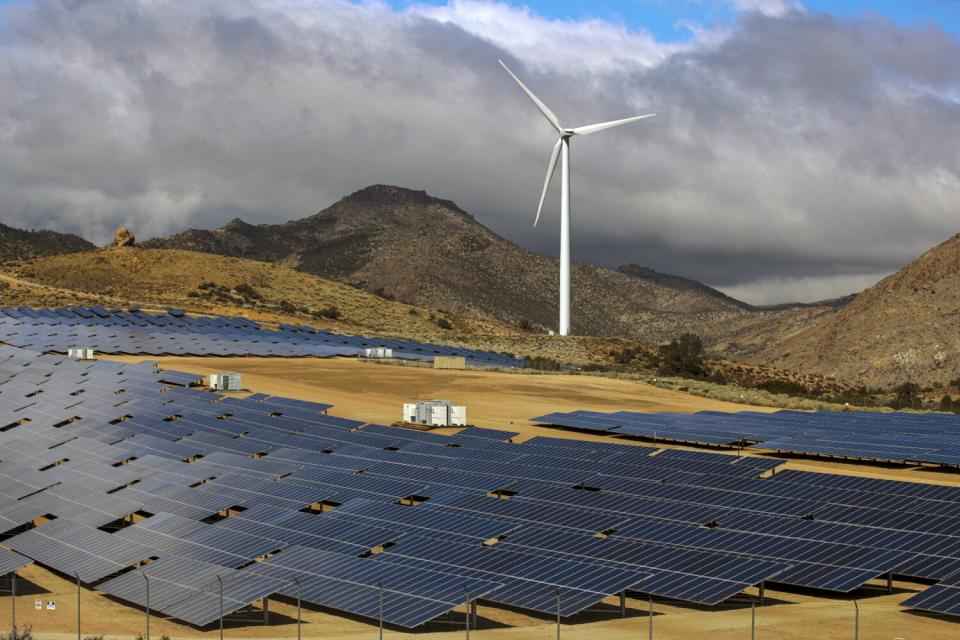 A field of solar panels as well as a wind turbine.