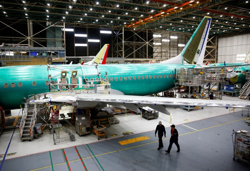 FILE PHOTO: Two workers walk under the wing of a 737 Max aircraft at the Boeing factory in Renton