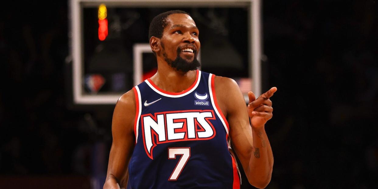 Kevin Durant smiles and points during a Nets game.