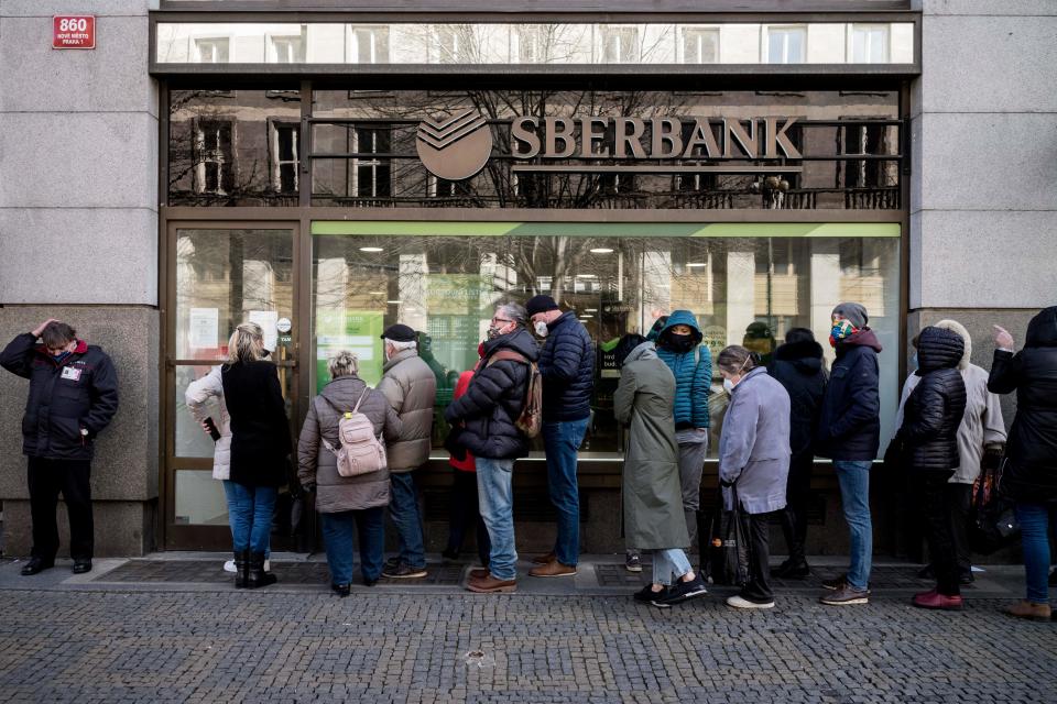 TOPSHOT - People queue outside a branch of Russian state-owned bank Sberbank to withdraw their savings and close their accounts in Prague on February 25, 2022, before Sberbank will close all its branches in the Czech Republic later in the day. - US President Biden was the first to announce sanctions, hours after Russian President Putin declared a 