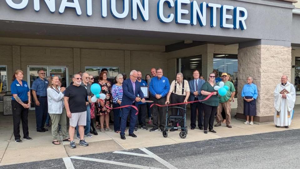 St. Vincent de Paul Director of Stores Support Jeff Beamguard cuts the ribbon at the Fairview Heights store’s grand opening. Store manager Dennis Chaney (holding frame) and U.S. Society of St. Vincent de Paul CEO David Barringer stand to the right of Beamguard.