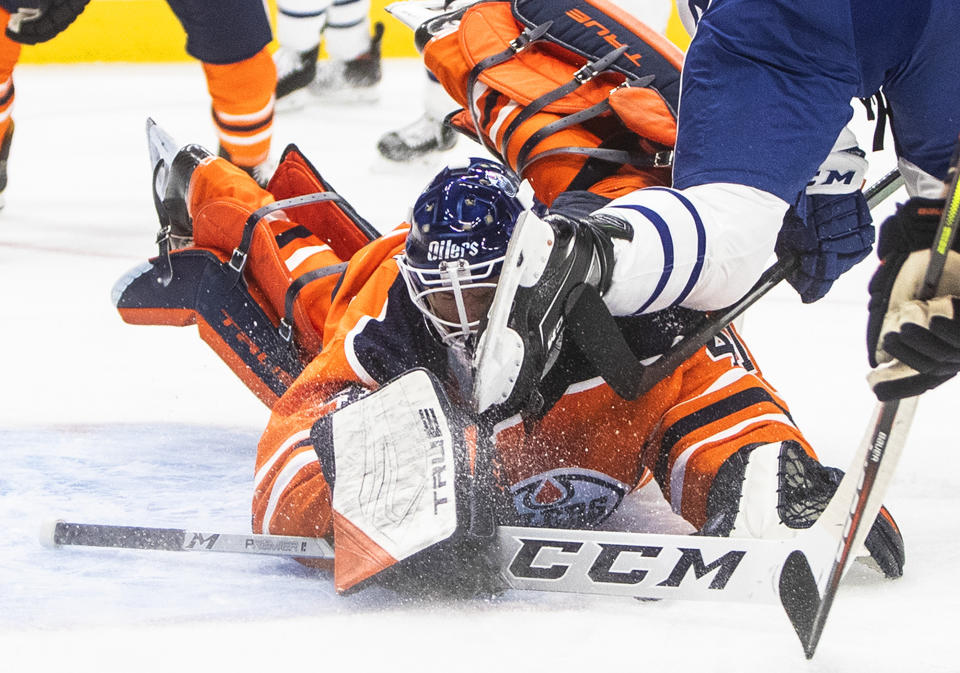 Edmonton Oilers goalie Mike Smith (41) makes the save as he is hit with a skate from a Toronto Maple Leafs player during the first period of an NHL game in Edmonton, Alberta, on Saturday, Feb. 27, 2021. (Jason Franson/The Canadian Press via AP)