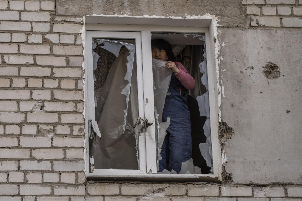 A woman places plastic over her damaged window after a Russian attack on the previous night, in the residential area of Mikolaiv, Ukraine, on Tuesday, March 29, 2022. Ukrainian President Volodymyr Zelenskyy says seven people were killed in a missile strike on the regional government headquarters in the southern city of Mykolayiv. (AP Photo/Petros Giannakouris)