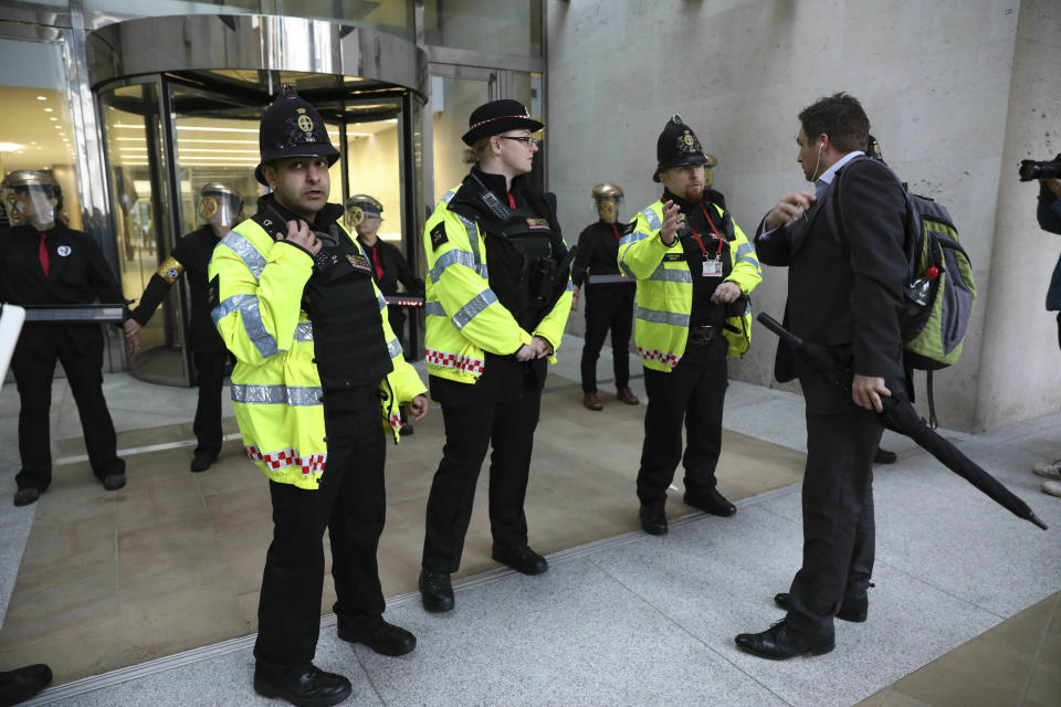 An office worker speaks to police after Extinction Rebellion climate protesters form a line after glueing themselves to block the entrances of the London Stock Exchange in the City of London, Thursday April 25, 2019. (Isabel Infantes/PA via AP)