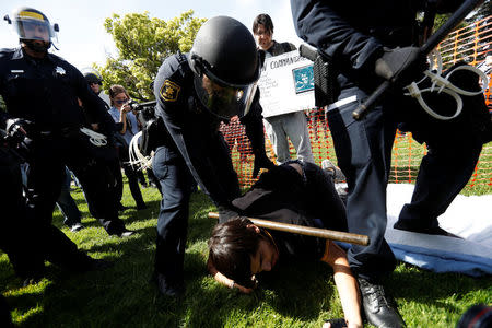 A police officer detains a demonstration as groups for and against U.S. President Donald Trump rally in Berkeley, California in Berkeley, California, U.S., April 15, 2017. REUTERS/Stephen Lam