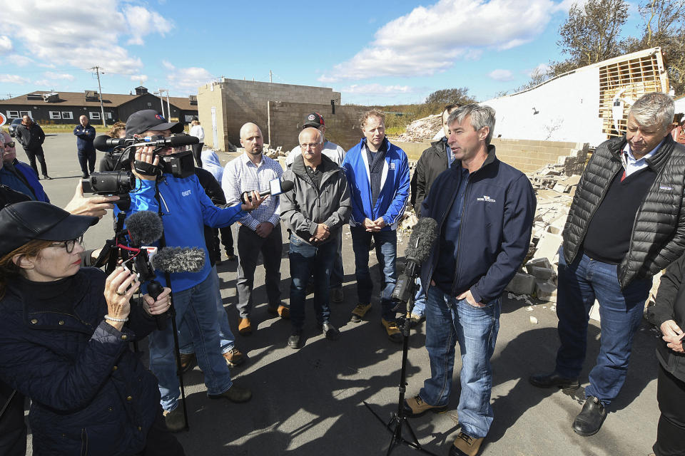 Nova Scotia Premier Tim Houston, right, gives a briefing on post-tropical storm Fiona and the government response in front of a destroyed structure in Glace Bay, Nova Scotia, Sunday, Sept. 25, 2022. A day after post-tropical storm Fiona left a trail of destruction through Atlantic Canada and eastern Quebec, residents of a coastal town in western Newfoundland continued to pick through wreckage strewn across their community, easily the most damaged area in the region. (Vaughan Merchant/The Canadian Press via AP)