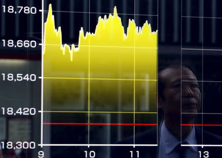 A pedestrian is reflected on an electronic board showing the graph of the recent fluctuations of the Japan's Nikkei average outside a brokerage in Tokyo, Japan, August 27, 2015. REUTERS/Yuya Shino