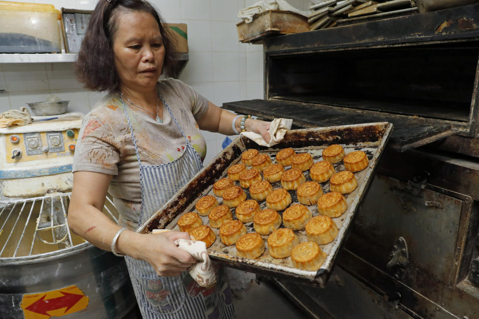 In this Friday, Aug. 9, 2019 photo, a staff member holds a tray of mooncakes with Chinese words "Hong Kong people" at Wah Yee Tang bakery in Hong Kong. A Hong Kong bakery is doing its part to support the city’s pro-democracy protest movement by making mooncakes with a message. At Wah Yee Tang, the traditional Chinese harvest festival treat comes with a twist: slogans opposing the city’s Beijing-backed government and promoting Hong Kong’s unique identity that have become popular rallying cries since the protests began two months ago. (AP Photo/Kin Cheung)