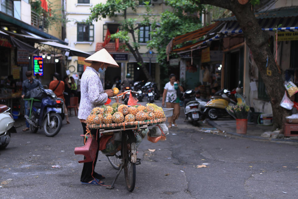 A fruit vender sells pineapples in a market in Hanoi, Vietnam on Sunday, Aug. 14, 2022. In the six months since Russia invaded Ukraine, the fallout from the war has had huge effects on the global economy. Though intertwined with other forces, the war has made problems like inflation much worse for people around the world. Soaring food and energy prices have turned into crises that are threatening to plunge millions of people into poverty and make recessions ever more likely. (AP Photo/Hau Dinh)