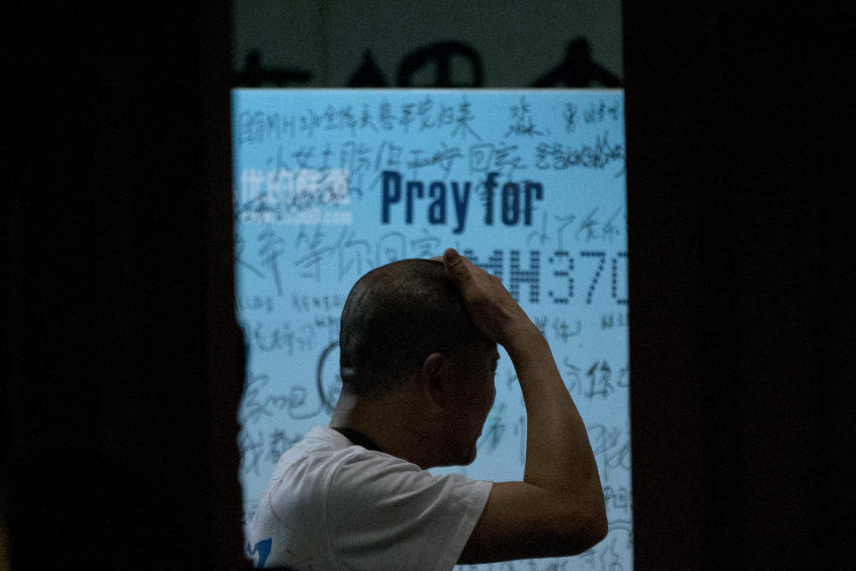 One of the relatives of Chinese passengers on board Malaysia Airlines Flight 370 rubs his head near a board covered with written wishes from relatives during a briefing given by Malaysian officials at a hotel in Beijing, China, Wednesday, March 26, 2014. Some of the wishes, partially seen, read, "Dear husband, you must stay strong, I am waiting for you. My dear, please be back soon." The search for the missing plane resumed Wednesday after fierce winds and high waves forced crews to take a break Tuesday. (AP Photo/Alexander F. Yuan)