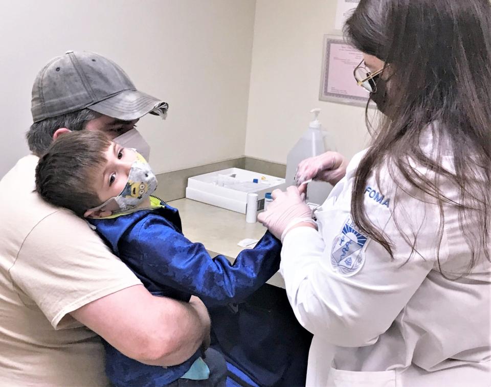 LECOM Elmira medical student Valerie Fiore performs a free lead screening on Lincoln Malloy, 5, at the Economic Opportunity Office in Elmira while his father Steven Malloy, of Horseheads, looks on.