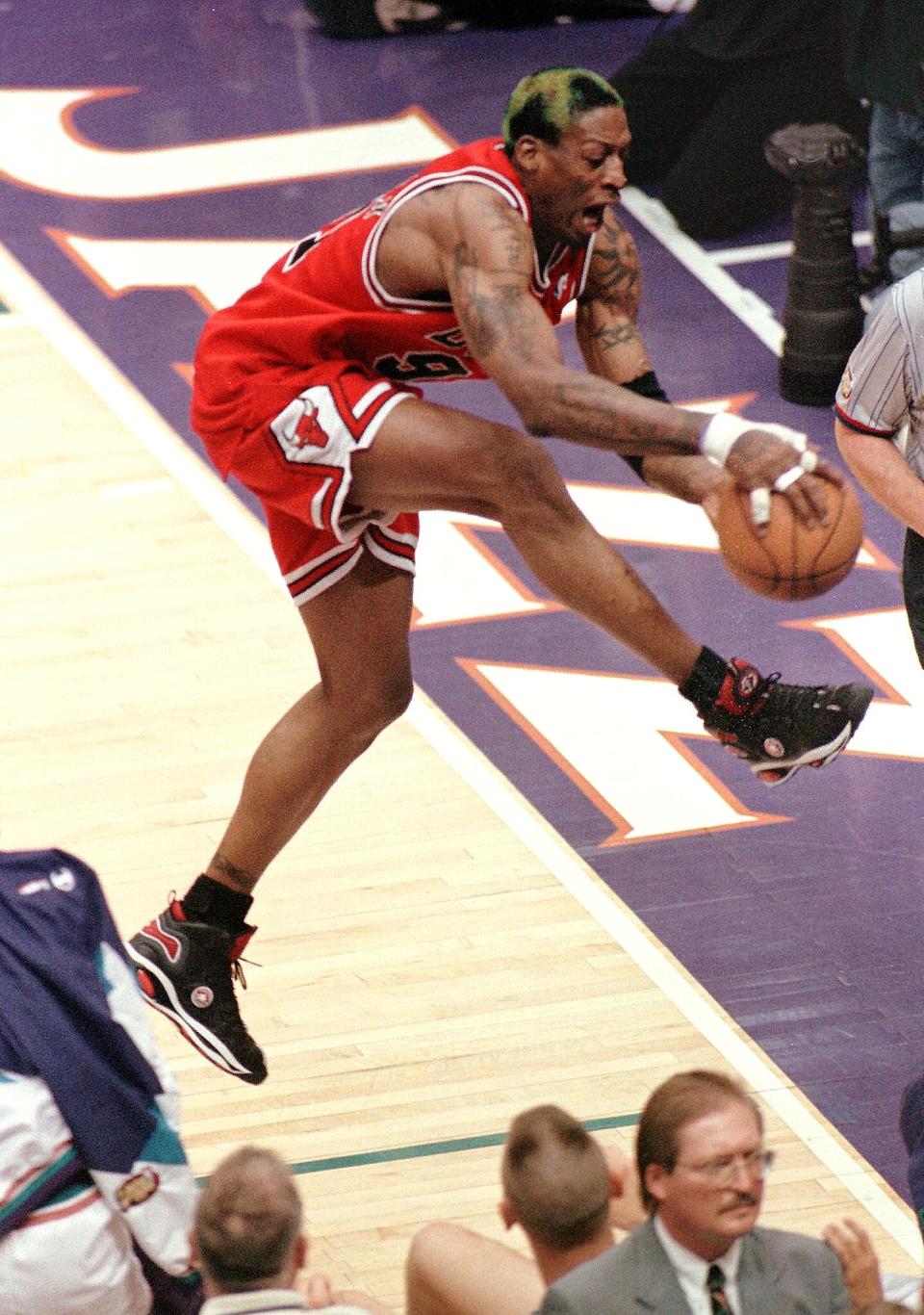 SALT LAKE CITY, UNITED STATES: Dennis Rodman of the Chicago Bulls flies over the Utah Jazz bench 05 June as he grabs a rebound during game two of the NBA Finals at the Delta Center in Salt Lake City, UT. The Bulls beat the Jazz 93-88 to even the best-of-seven series at 1-1. AFP PHOTO George FREY (Photo credit should read GEORGE FREY/AFP via Getty Images)