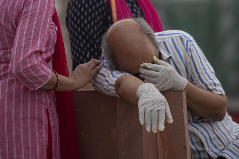 A man reacts before the cremation of his relative, who died from the coronavirus disease (COVID-19), on the banks of the river Ganges at Garhmukteshwar