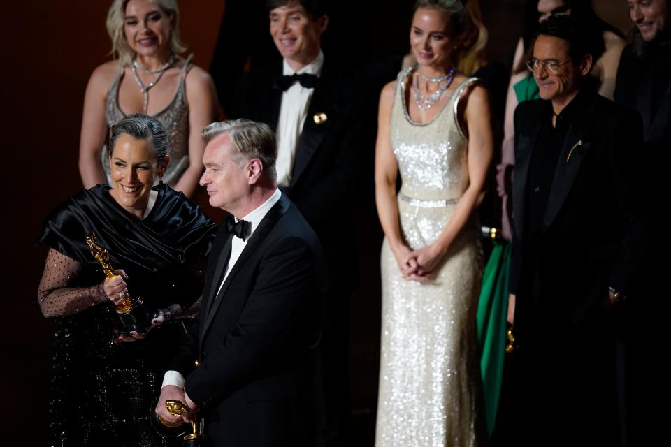 Emma Thomas and Christopher Nolan accept the award for best motion picture for "Oppenheimer" as the film's stars stand behind them on stage.