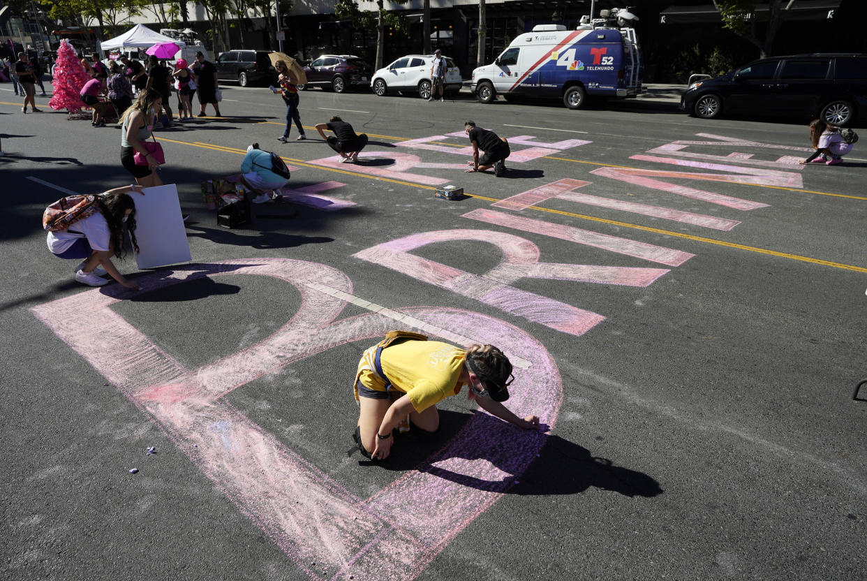 Stacy Moffatt, of Costa Mesa, Calif., bottom, and other Britney Spears supporters color in a "Free Britney" message on Grand Ave. outside a hearing concerning the pop singer's conservatorship at the Stanley Mosk Courthouse, Friday, Nov. 12, 2021, in Los Angeles. (AP Photo/Chris Pizzello)