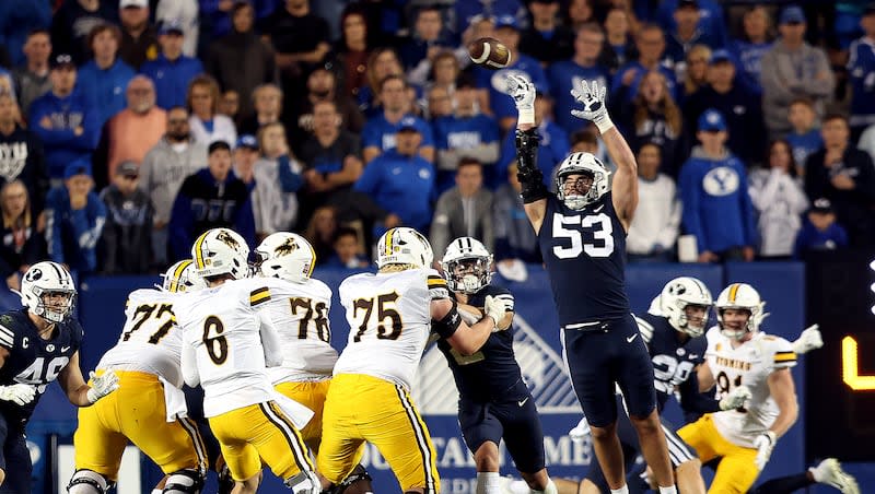 BYU Cougars defensive lineman Fisher Jackson (53) knocks down a Wyoming Cowboys quarterback Andrew Peasley (6) as BYU and Wyoming play at LaVell Edwards Stadium in Provo on Saturday, Sept. 24, 2022. BYU won 38-24.