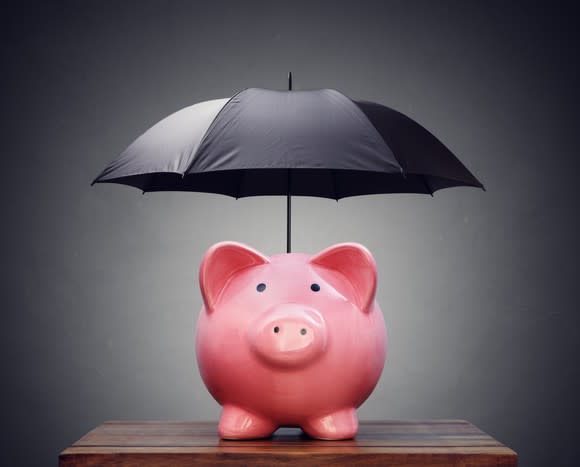 Pink piggy bank with a black umbrella over it.