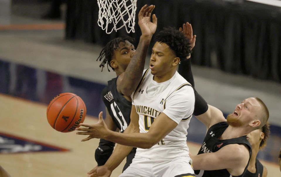 Wichita State guard Ricky Council IV, center, tries to pass around Cincinnati forward Tari Eason, left, and Cincinnati guard Mason Madsen, right, during the first half of an NCAA college basketball game in the semifinal round of the American Athletic Conference men's tournament Saturday, March 13, 2021, in Fort Worth, Texas. (AP Photo/Ron Jenkins)