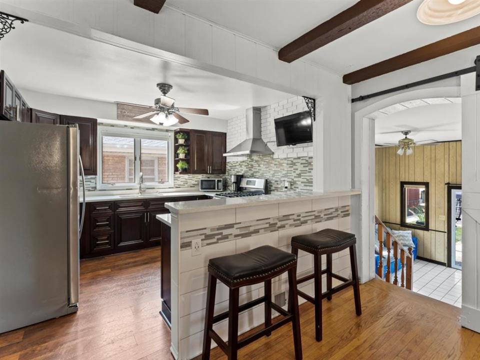 the kitchen with stools, stainless steel appliances, and wood beams in house for sale near chicago