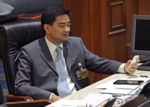 Thai Prime Minister Abhisit Vejjajiva looks at his mobile phone during the second-day of a no-confidence debate at Parliament in Bangkok. Vejjajiva survived a no-confidence motion brought by opposition lawmakers seeking to inflict damage ahead of upcoming elections