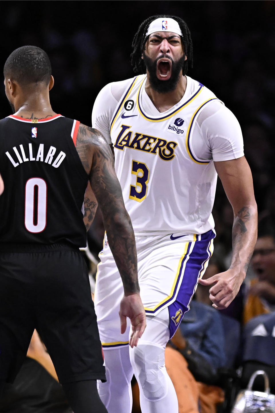 Los Angeles Lakers forward Anthony Davis, right, reacts after dunking against Portland Trail Blazers guard Damian Lillard (0) during the second half of an NBA basketball game Sunday, Oct. 23, 2022, in Los Angeles. (AP Photo/Alex Gallardo)
