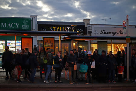 Commuters queue for a bus on a high street in Dagenham, east London, Britain, March 18, 2019. REUTERS/Hannah McKay