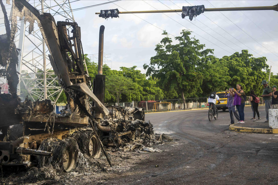 A burnt out truck used by gunmen smolders on an intersection, a day after street battles between gunmen and security forces in Culiacan, Mexico, Friday Oct. 18, 2019. Mexican security forces backed off an attempt to capture a son of imprisoned drug lord Joaquin "El Chapo" Guzman after finding themselves outgunned in a ferocious shootout with cartel enforcers that left at least eight people dead and more than 20 wounded, authorities said. (AP Photo/Augusto Zurita)