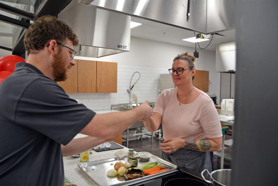 Hunter Atterbury, Food Bank for Central and Northeast Missouri neighbor services lead, accepts a creamy lentil and vegetable soup sample Monday from Trish Sieckmann, CoMo Cooks kitchen manager, who was onsite to conduct a cooking demonstration at The Food Bank Market's grand opening at 705 Business Loop 70 W.