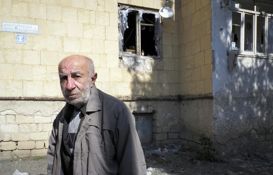 Vartan Grigoryan stands near his apartment, damaged by shelling by Azerbaijan's artillery, during a military conflict in Stepanakert, the separatist region of Nagorno-Karabakh, Saturday, Oct. 10, 2020. Armenia and Azerbaijan have agreed to a Russia-brokered cease-fire in Nagorno-Karabakh after two weeks of heavy fighting that marked the worst outbreak of hostilities in the separatist region in more than a quarter-century. (AP Photo)