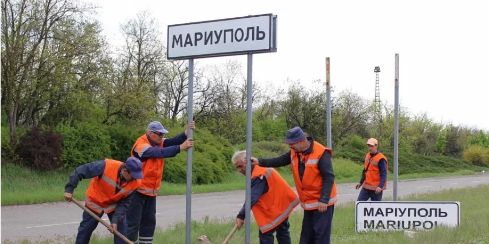 Locals change a Ukrainian road sign "Mariupol" to the same sign in the Russian language <span class="copyright">Petro Andriushchenko</span>