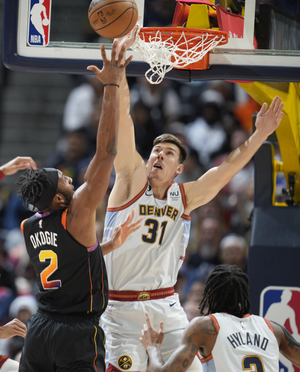 Phoenix Suns forward Josh Okogie, left, drives to the rim as Denver Nuggets forward Vlatko Cancar defends in the first half of an NBA basketball game Wednesday, Jan. 11, 2023, in Denver. (AP Photo/David Zalubowski)