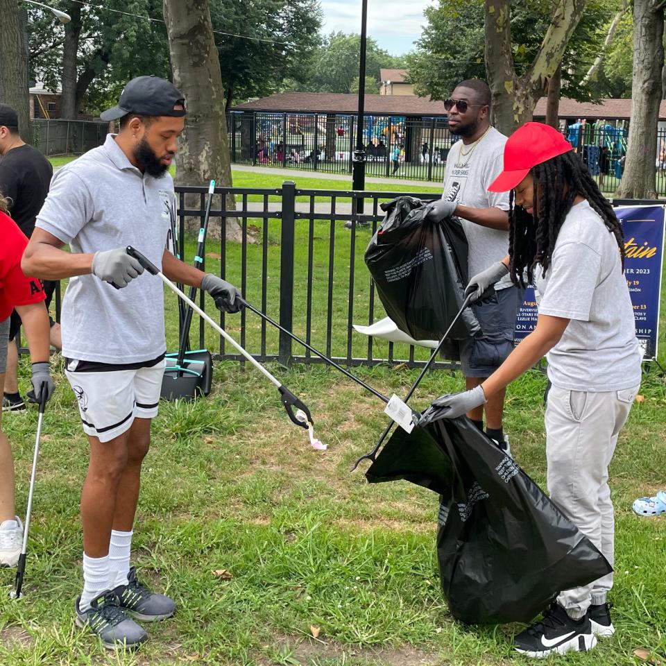 Walk a Mile N Our Shoes CEO Eugene Campbell III of Carteret (left) helps volunteers clean up West Side Avenue in Jersey City.