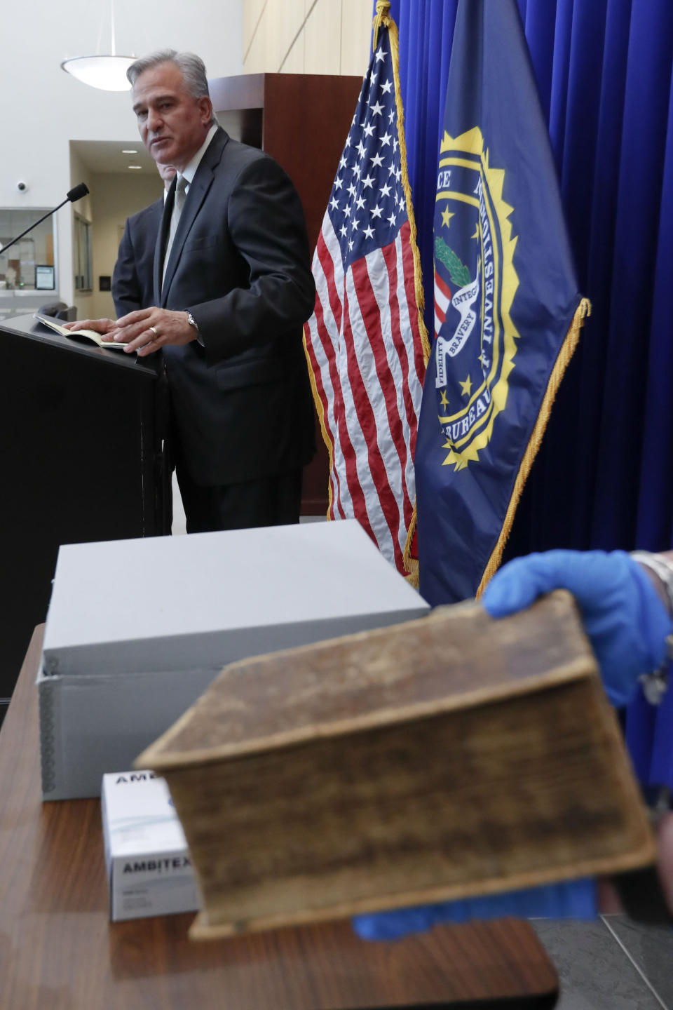 Allegheny County District Attorney Stephen Zappala talks about the efforts and ultimate recovery of the Breeches Edition Bible that FBI supervisory special agent Shawn Brokos holds during a news conference, Thursday, April 25, 2019, in Pittsburgh. The Bible that was published in 1615 was stolen from the Carnegie Library in Pittsburgh in the 1990's. It was traced to the American Pilgrim Museum in Leiden, Netherlands. (AP Photo/Keith Srakocic)