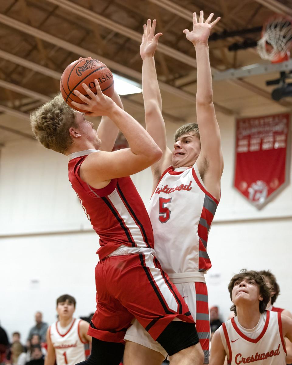 Field senior Braxton Baumberger goes up for a shot while Crestwood junior Charlie Schweickert leaps up for the block during Monday night’s basketball game at Crestwood High School.