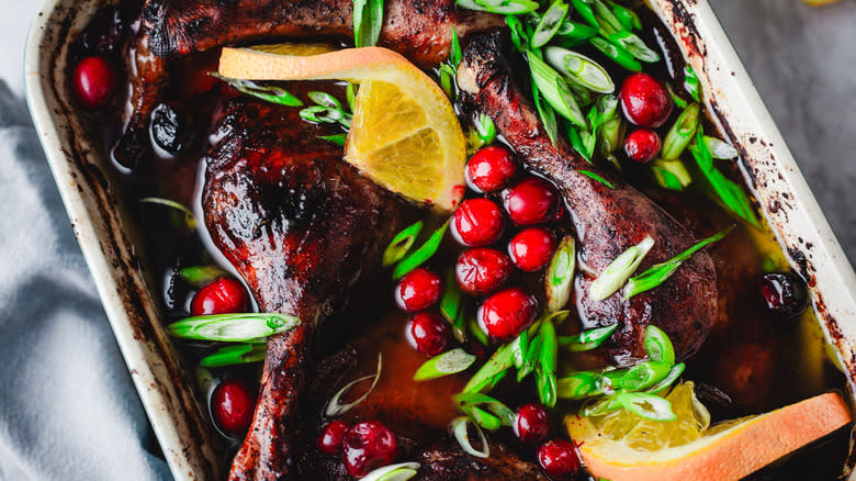 Close up roast duck legs with cranberries and orange