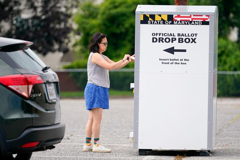 A woman drops a ballot into a drop box while casting her vote during Maryland's primary election, Tuesday, July 19, 2022, in Baltimore.