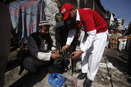 Security officials and rescue workers collect evidence at the site of a bomb blast in Charsadda district in the outskirts of Peshawar April 22, 2014. REUTERS/Fayaz Aziz