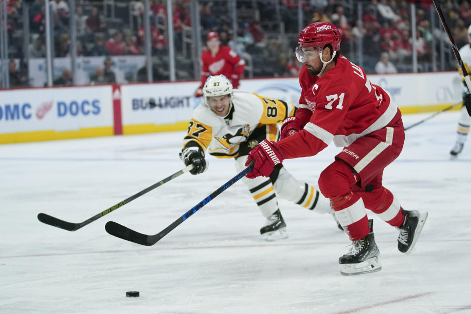 Detroit Red Wings center Dylan Larkin (71) skates with the puck as Pittsburgh Penguins center Sidney Crosby (87) defends during the second period of a preseason NHL hockey game Monday, Oct. 3, 2022, in Detroit. (AP Photo/Paul Sancya)