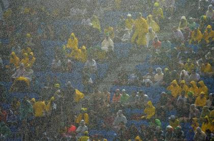Fans sit under pouring rain during the match between Mexico and Cameroon. (AFP)