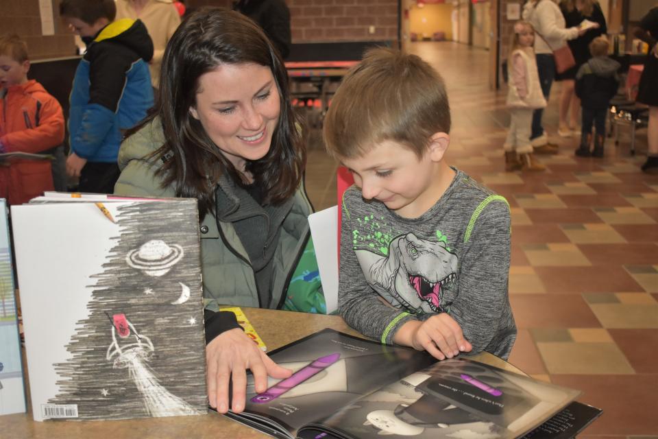 Addison Elementary School fifth grader Wesley Sampsell, 5, right, reads the book "Creepy Crayon" by Aaron Reynolds with his mom, Katie Sampsell, during a literacy night program Tuesday at Addison Middle/High School that was conducted by teacher education students at Adrian College.
