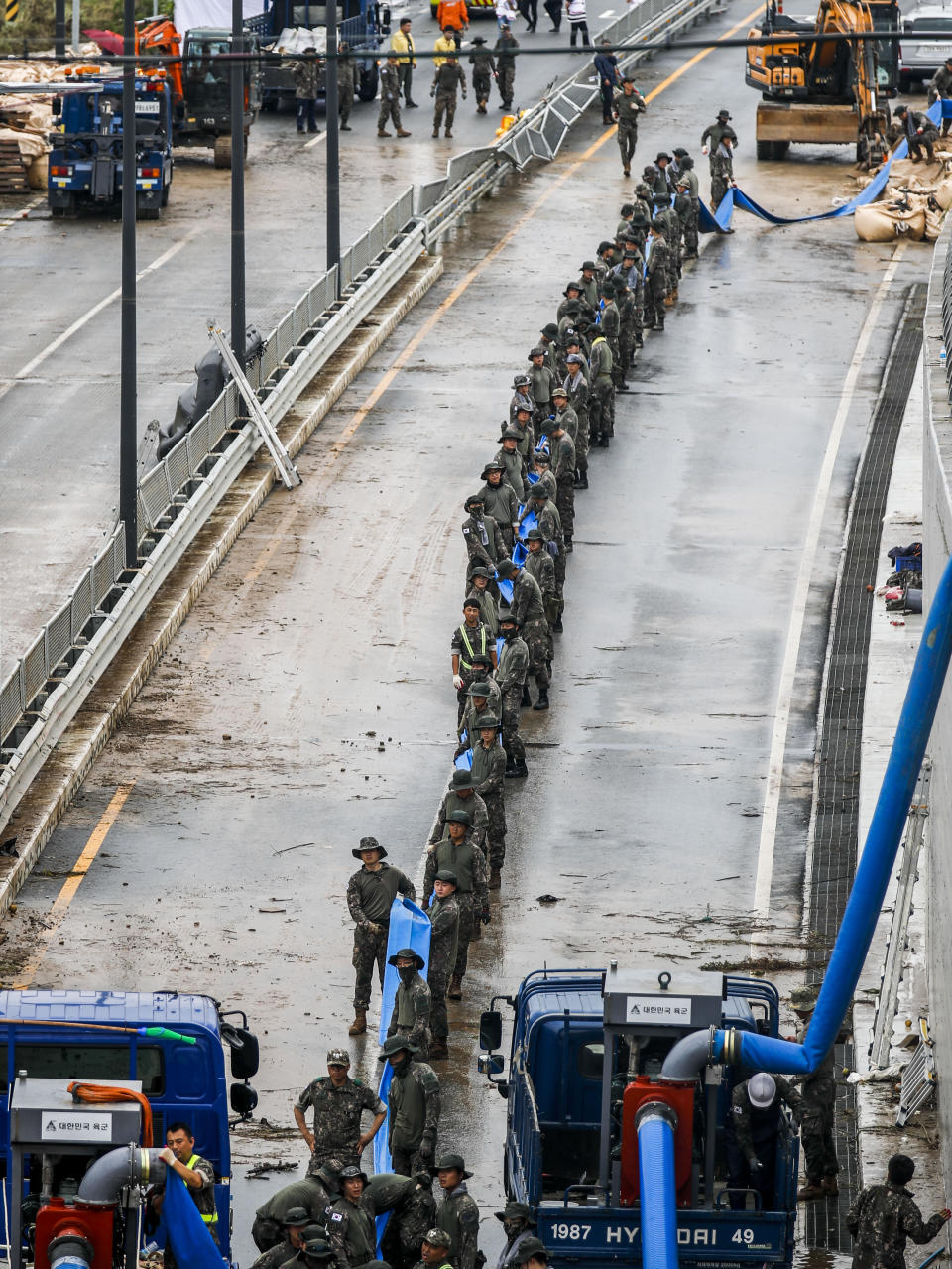 South Korean soldiers hold a tube to pump water out of a tunnel along a road leading to an underground tunnel in Cheongju, South Korea, Sunday, July 16, 2023. Days of heavy rain triggered flash floods and landslides and destroyed homes, leaving scores of people dead and forcing thousands to evacuate, officials said Sunday. (Chung Byung-hyuck/Newsis via AP)