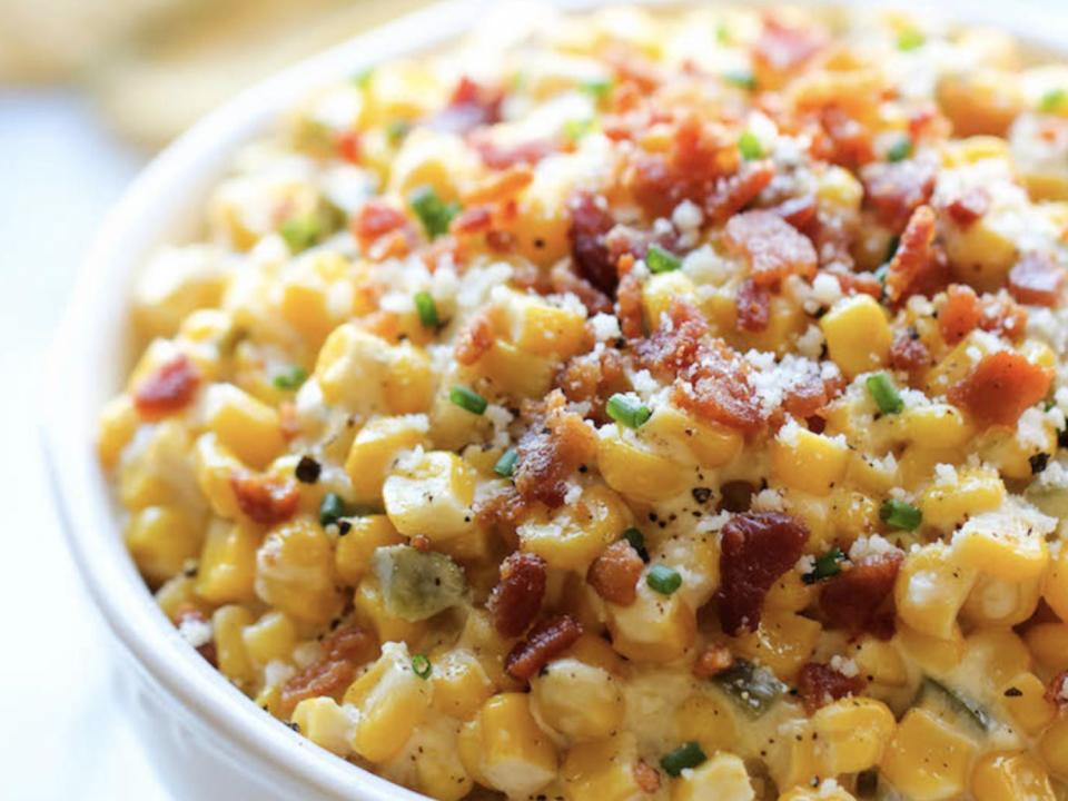 corn and jalapeno dip in a white bowl with bacon on top