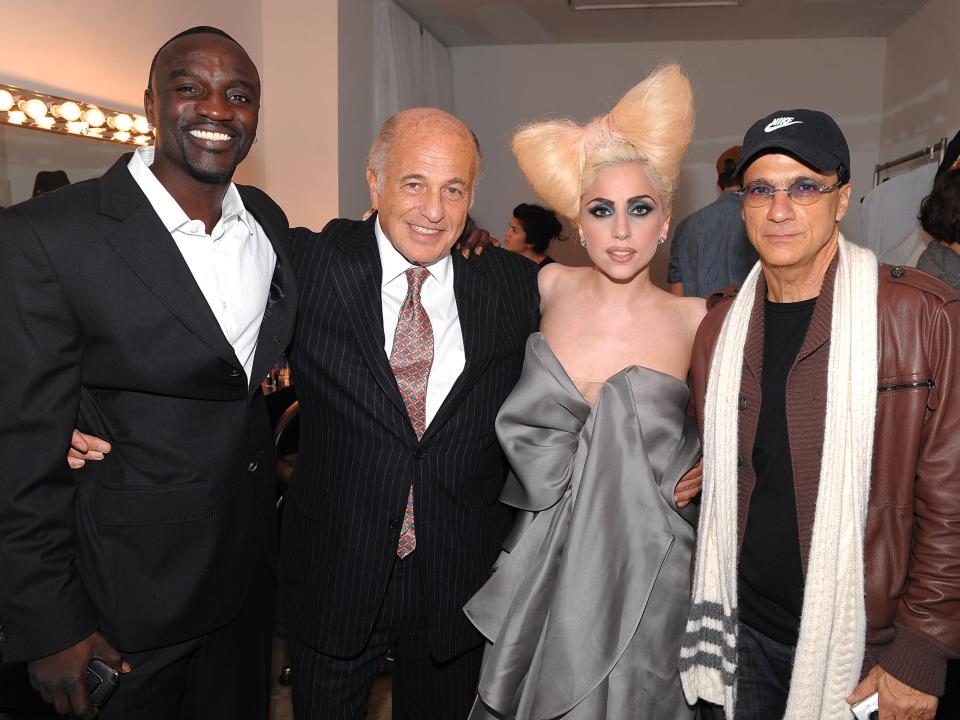 Akon, Morris, Gaga with a bow-shaped platinum hair updo and grey strapless dress, and Iovine posing for a photo.