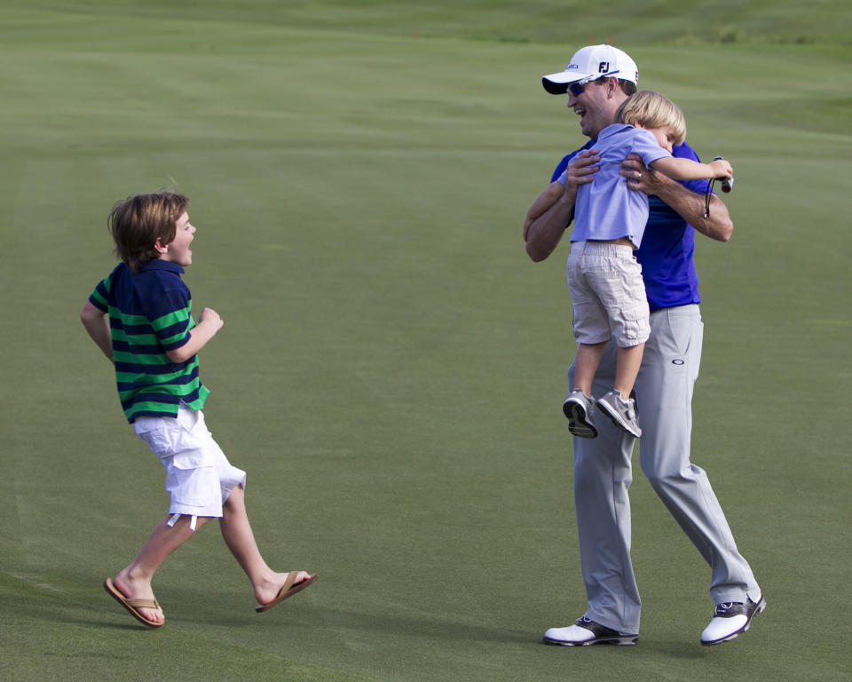 Zach Johnson, picks up his son Wyatt, 3, as son Will, 7, runs out to greet him after Johnson won the final round of the Tournament of Champions golf tournament, Monday, Jan. 6, 2014, in Kapalua, Hawaii. (AP Photo/Marco Garcia)